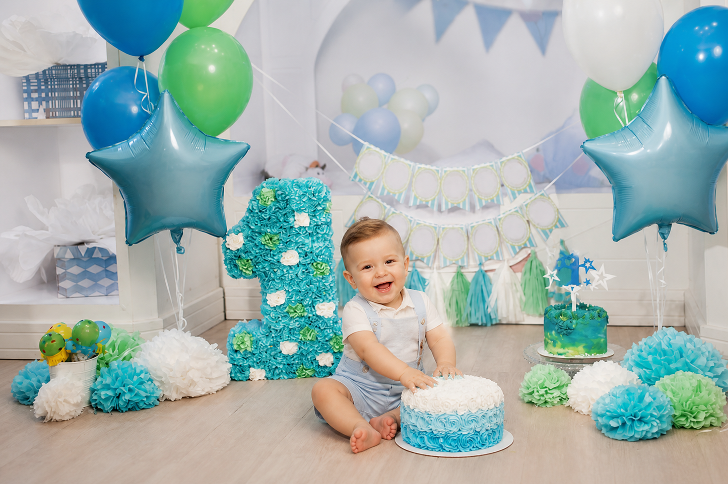 One-year-old boy cake smash scene with blue and green balloon first birthday backdrop