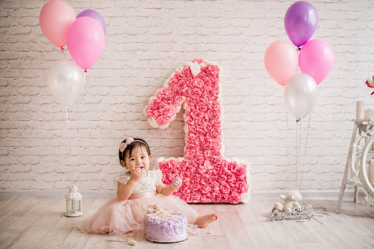 One-year-old girl cake smash scene with pink floral number one birthday backdrop
