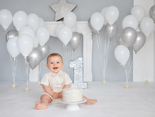 One-year-old cake smash portrait styled with the White and Silver Balloon First Birthday Backdrop